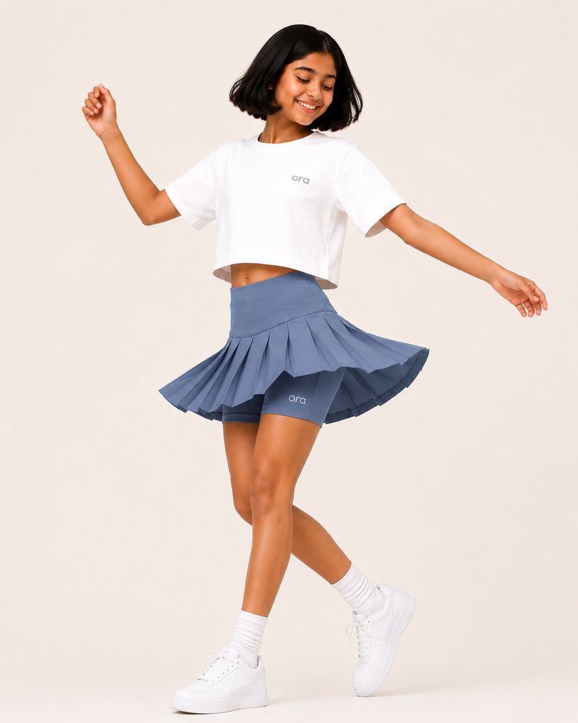 Tween in Ora cropped boxy tee and blue pleated skort, dancing